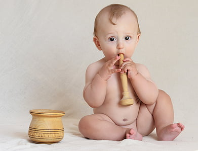 baby holding pestle beside mortar