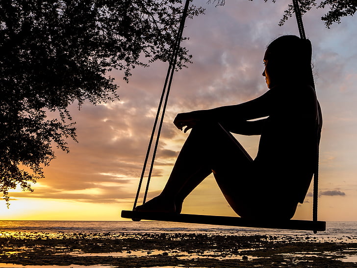 silhouette of woman sitting on swing