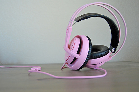 closeup photo of pink corded headphones on wooden panel