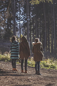 three woman standing in front of trees