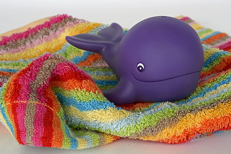 purple plastic whale toy on multicolored towel