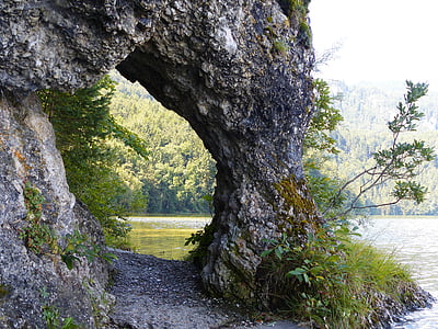 rock formation arch beside body of water during daytime