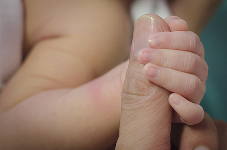 baby holding person's finger
