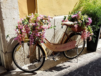 yellow and black bicycle with basket of flowers near wall during daytime