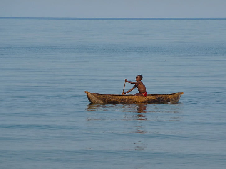 boy rowing in brown canoe