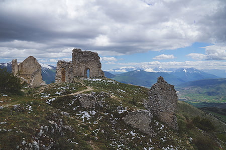 ruins on mountain under blue sky and cloudy sky during daytime