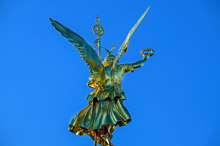 photo of gold-colored statue under blue sky at daytime