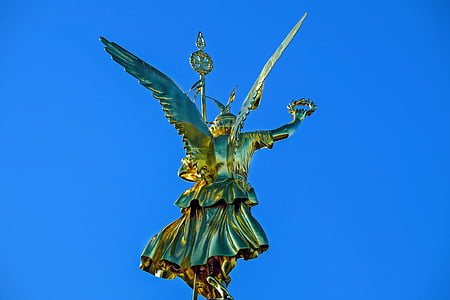photo of gold-colored statue under blue sky at daytime