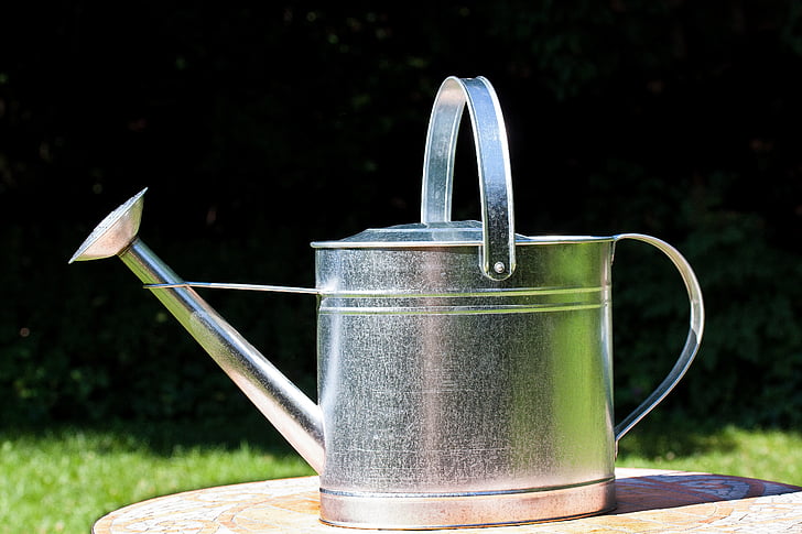 silver watering can on brown surface