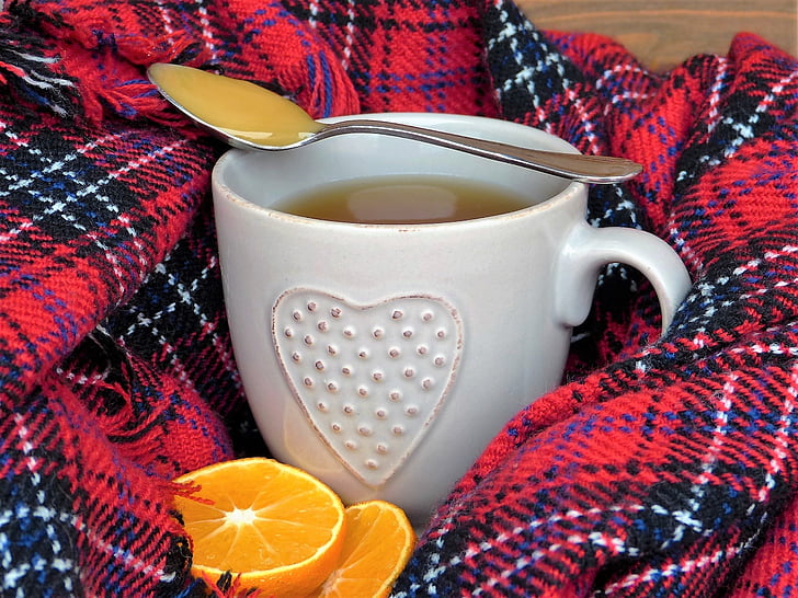 stainless steel spoon on top of white ceramic mug beside sliced orange fruit