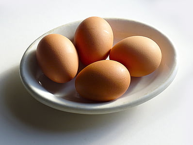 four brown eggs on white ceramic tray