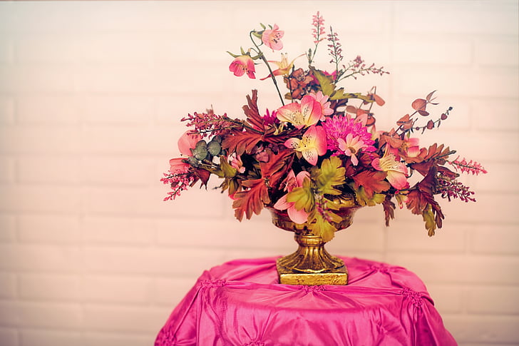 pink petaled flower with vase on table covered with pink tablecloth