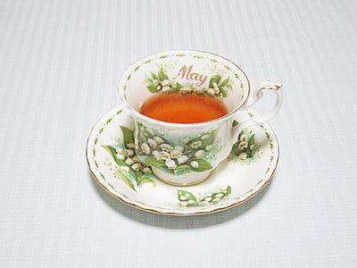 white and green floral teacup filled with brown liquid on saucer
