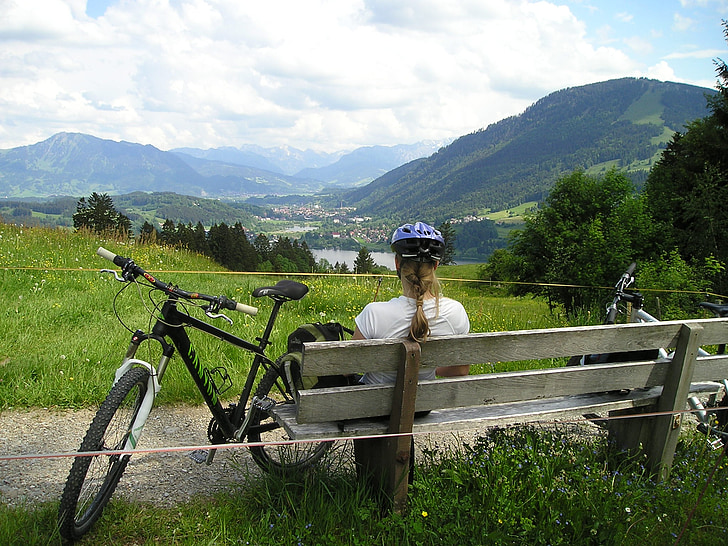 woman in white top sitting beside on bench beside bicycle