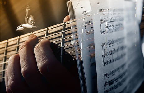 closeup photo of person playing guitar with musical notes
