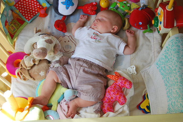 baby sleeping while surrounded by toys
