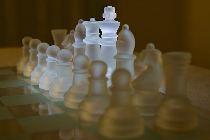 frosted glass chess piece set on chessboard