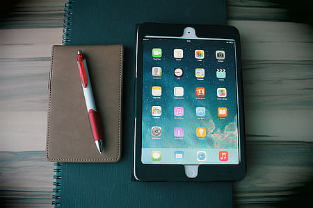white iPad with black case on green notebook