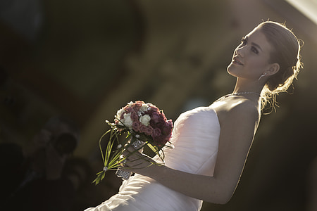 woman in white strapless wedding dress holding flower bouquet in hand