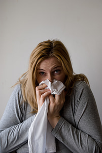 woman sneezing on white textile