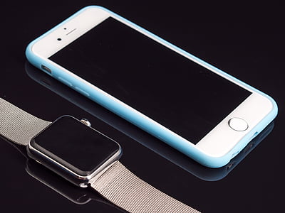 silver iPhone 6 and blue case beside Apple Watch with Milanese Loop