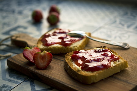 shallow focus photography of loaf bread with strawberry jam on brown wooden chopping board