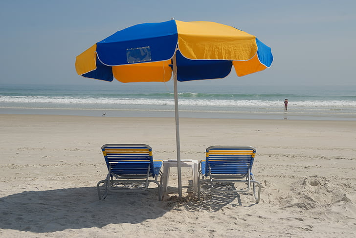 blue-and-yellow lounger chairs with umbrella on the beach during daytime
