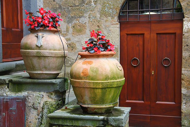 two mossy brown pots with red flowers