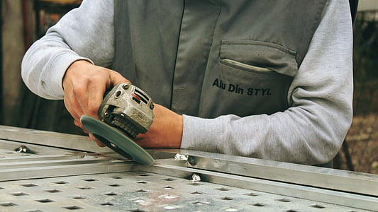 man holding gray cordless angle grinder
