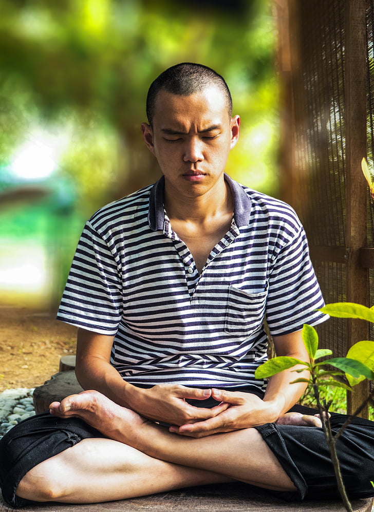 man meditating beside tree