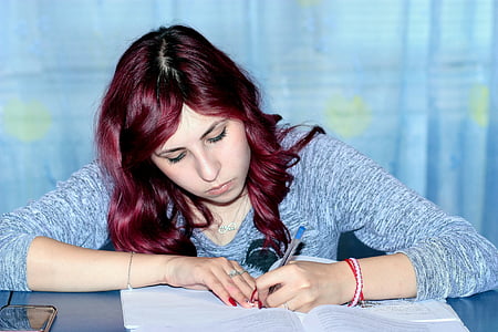 woman wearing gray long-sleeved shirt writing on paper