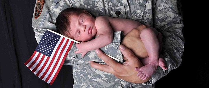 soldier carrying baby with U.S.A. flag