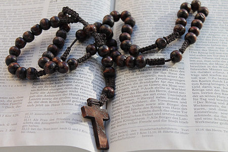 brown rosary on opened bible