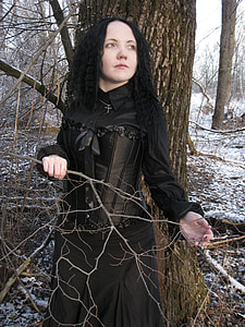 woman in black Victorian era dress near brown tree