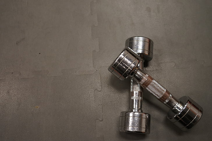 pair of grey fixed weight dumbbells on grey puzzle mat