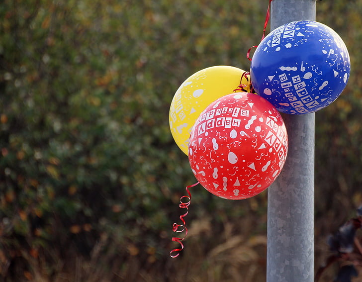 yellow, red, and blue balloons beside metal pipe