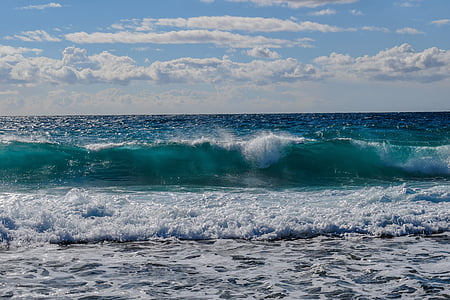 green and blue water beach with waves under white clouds blue skies