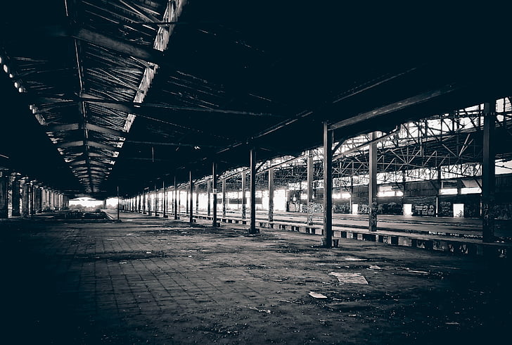 grayscale photography of railway beside station