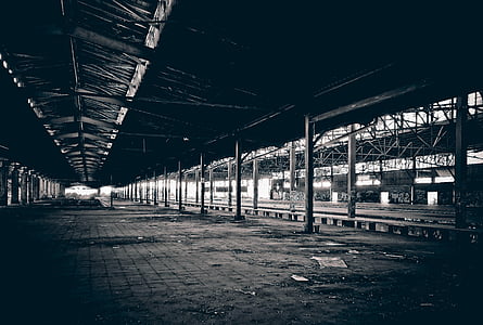 grayscale photography of railway beside station