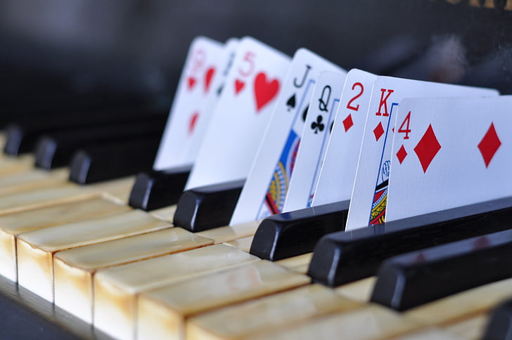 close up photography of playing cards put in between piano keys