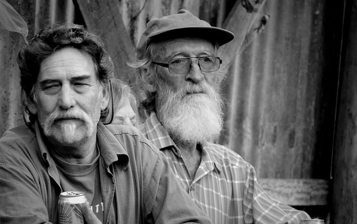 grayscale photography of two men sitting beside each other