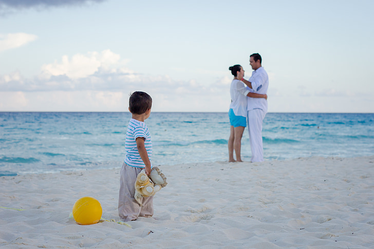 boy wearing white t-shirt staring on man and woman standing on shoreline