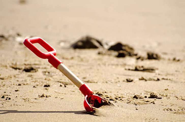 red and white sand shovel on sand
