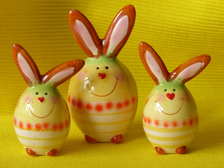 three yellow-red-and-white ceramic bunny figurines