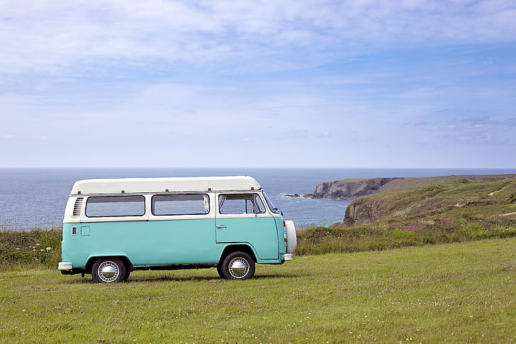 teal and white Volkswagen van parked on green grass field near ocean during daytrime