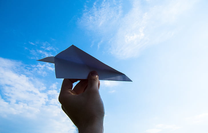 person holding paper plane during daytime