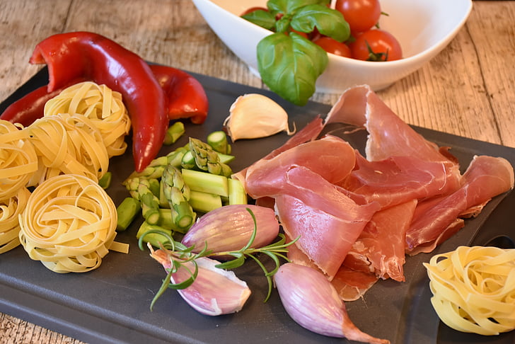 sliced meat, pasta, and vegetables on chopping board