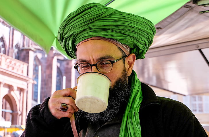 man holding white mug while drinking