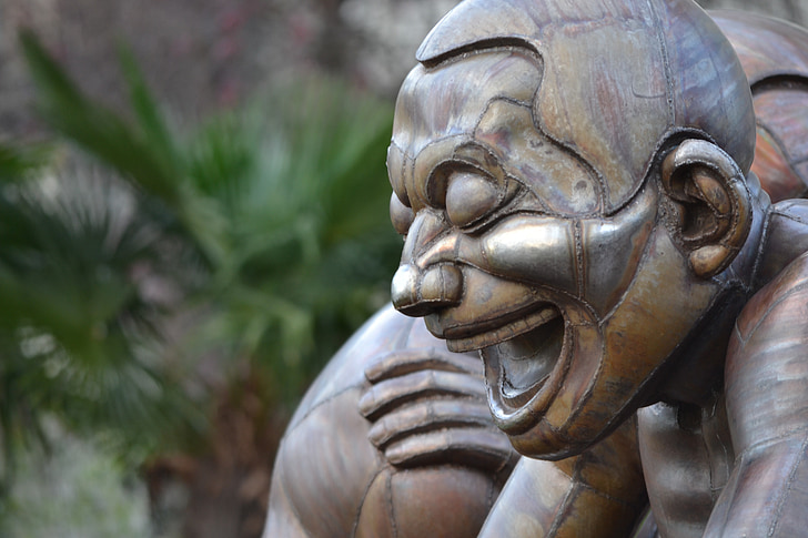brown laughing statue of man closeup photography