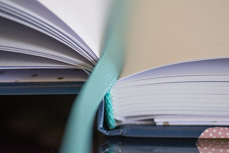 close-up photography of open white book pages with green bookmark